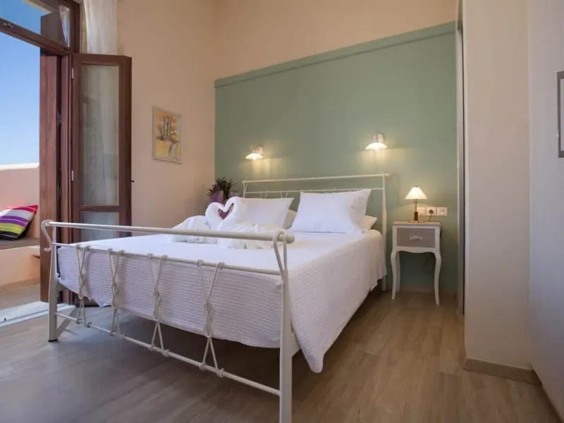 Bedroom with iron bed frame and balcony door, Villa Theta